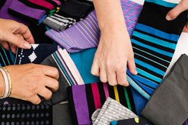 Hands selecting colorful patterned Dr. Segal’s socks, including striped and polka dot styles for everyday comfort.