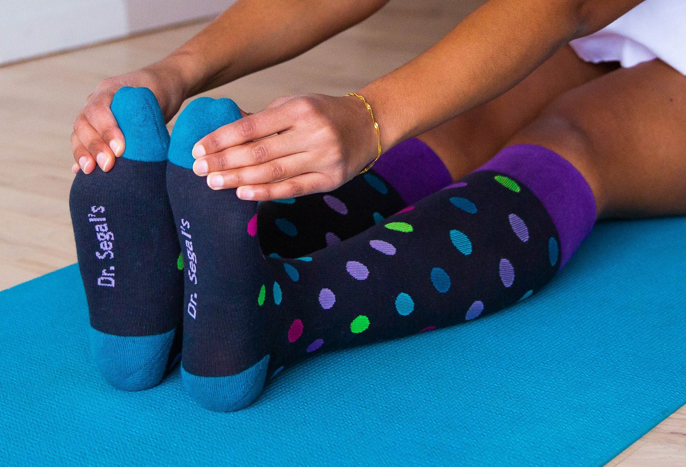 Person stretching on a yoga mat while wearing colorful compression socks, showing a recovery habit for heavy legs